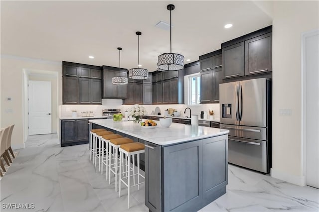 kitchen featuring a center island, a kitchen breakfast bar, hanging light fixtures, appliances with stainless steel finishes, and dark brown cabinetry