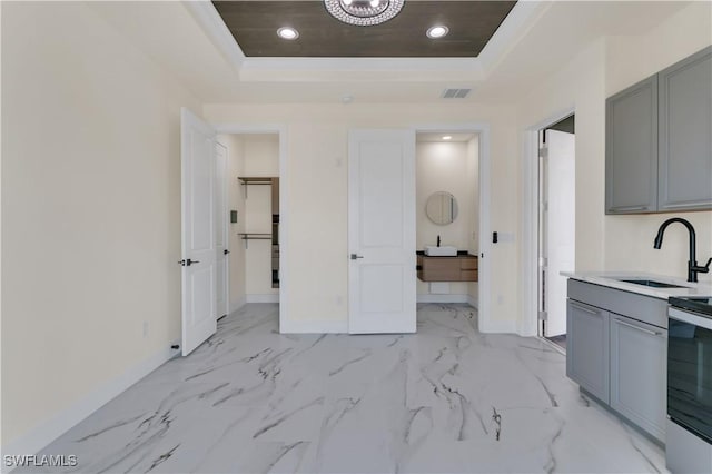 kitchen featuring a tray ceiling, gray cabinetry, sink, and electric range oven