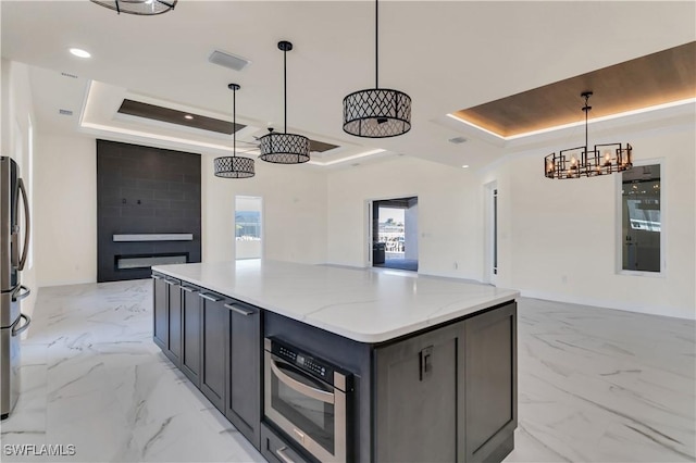 kitchen with pendant lighting, a kitchen island, and a raised ceiling