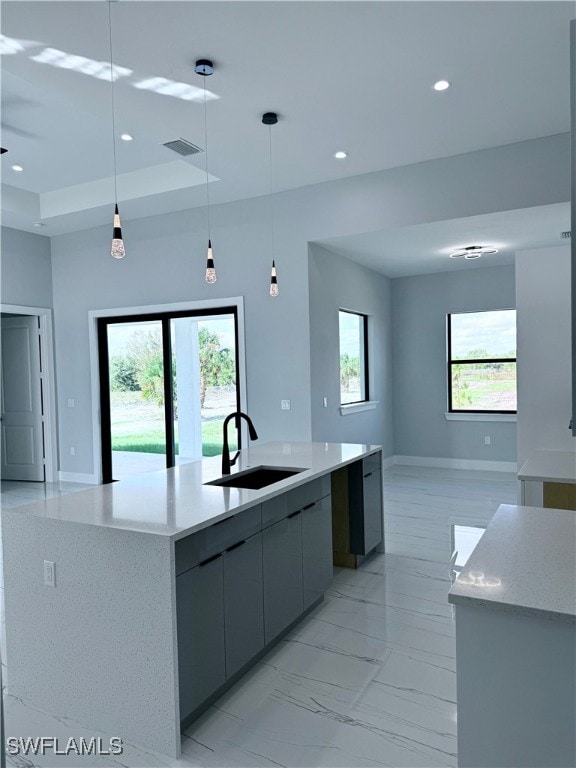 kitchen featuring gray cabinets, hanging light fixtures, a healthy amount of sunlight, and sink