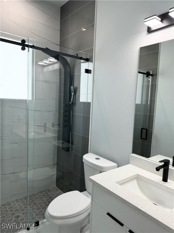 bathroom with vanity, toilet, and a shower with shower door