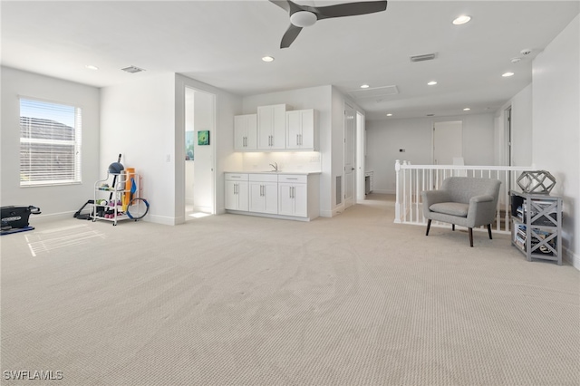 living area featuring ceiling fan, sink, and light carpet