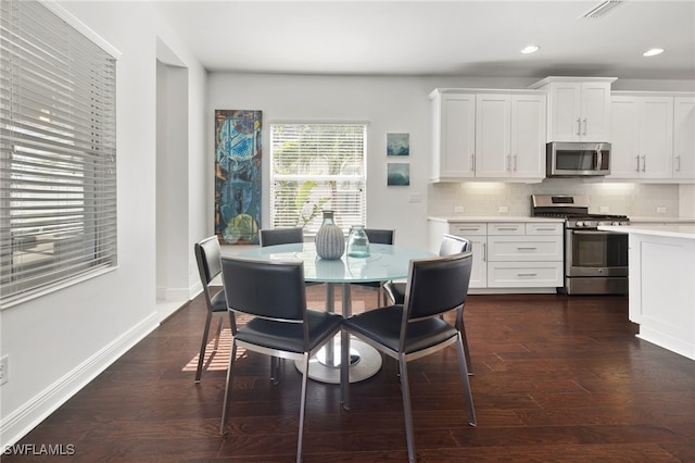 kitchen featuring dark hardwood / wood-style floors, decorative backsplash, white cabinetry, and stainless steel appliances