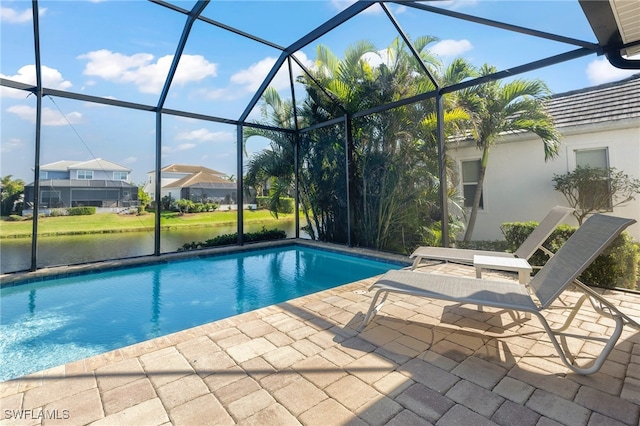 view of pool with glass enclosure, a water view, and a patio