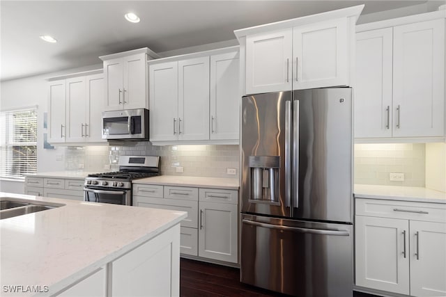 kitchen with light stone countertops, stainless steel appliances, dark hardwood / wood-style flooring, decorative backsplash, and white cabinets