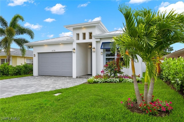 view of front of property with stucco siding, a standing seam roof, an attached garage, decorative driveway, and a front yard