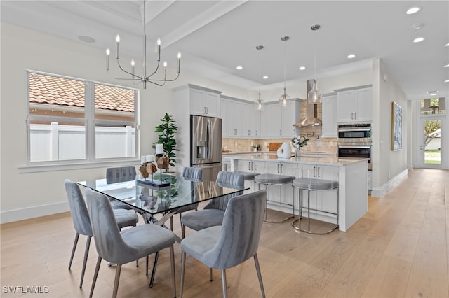 dining area featuring a chandelier, beam ceiling, and light hardwood / wood-style flooring