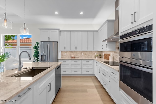 kitchen featuring white cabinetry, sink, light hardwood / wood-style floors, decorative light fixtures, and appliances with stainless steel finishes