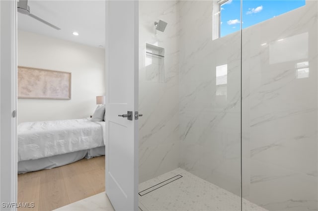 bathroom with a tile shower and hardwood / wood-style floors