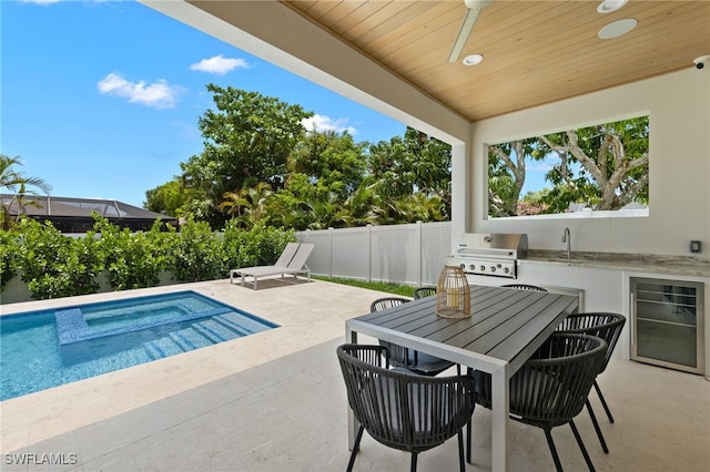 view of swimming pool with ceiling fan, area for grilling, sink, and a patio