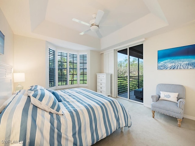 bedroom with ceiling fan, a tray ceiling, carpet, and access to outside