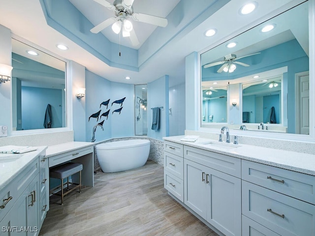 bathroom with vanity, hardwood / wood-style flooring, plus walk in shower, and ceiling fan