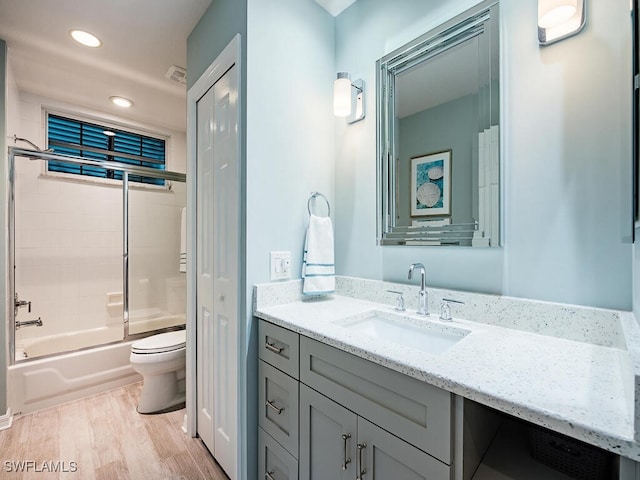 full bathroom with vanity, toilet, combined bath / shower with glass door, and wood-type flooring