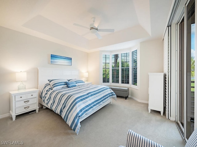 carpeted bedroom with ceiling fan and a tray ceiling