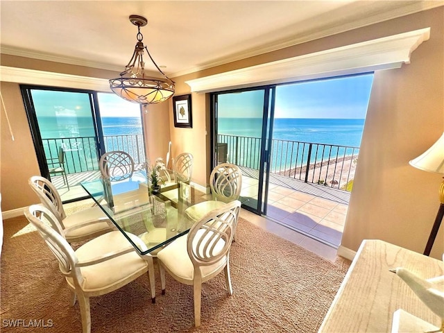 carpeted dining space with crown molding, a water view, and a healthy amount of sunlight