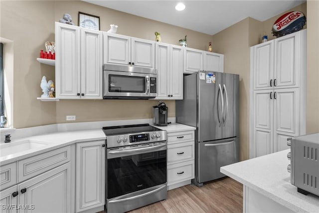 kitchen featuring stainless steel appliances, sink, white cabinets, and light hardwood / wood-style floors