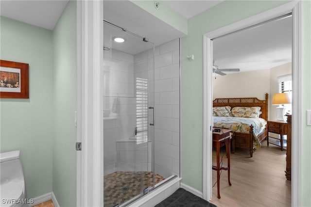 bathroom with hardwood / wood-style flooring, ceiling fan, toilet, and a shower with door