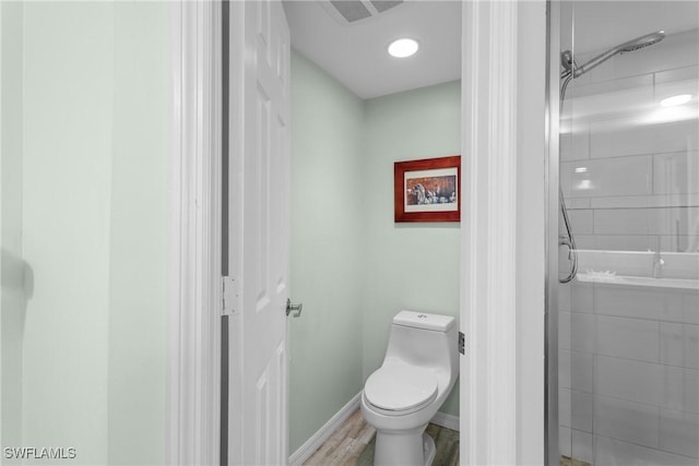 bathroom with hardwood / wood-style flooring, toilet, and a shower with door