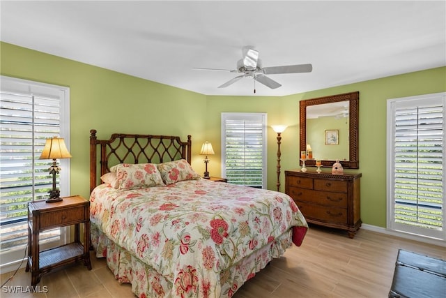 bedroom with multiple windows, light hardwood / wood-style flooring, and ceiling fan