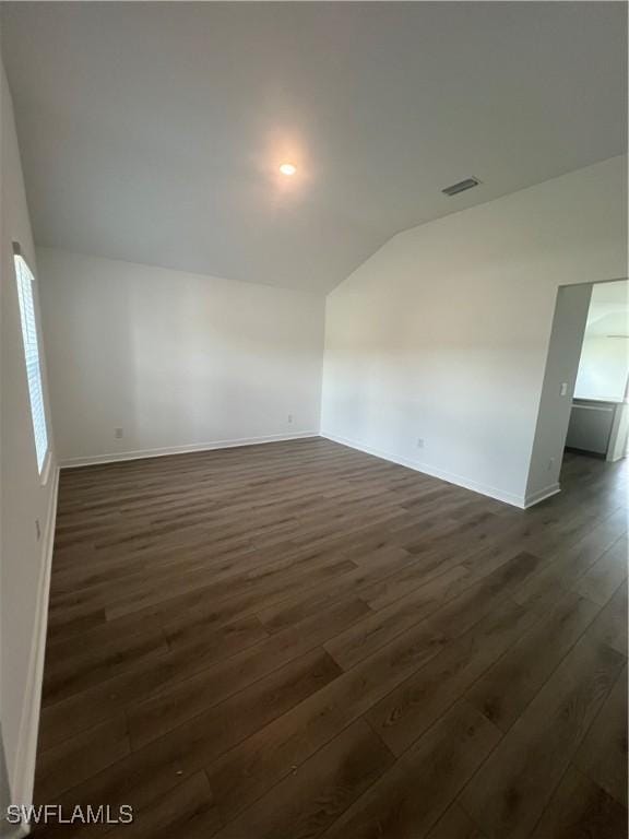 spare room featuring dark hardwood / wood-style flooring and vaulted ceiling