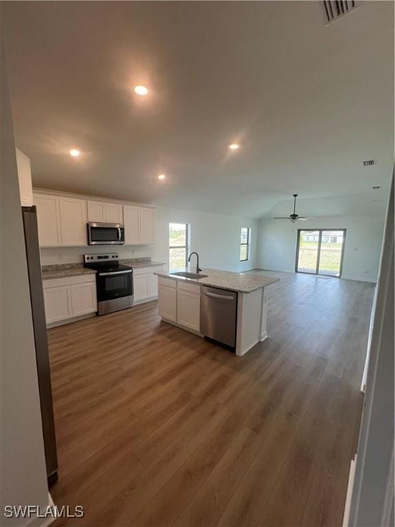 kitchen with sink, white cabinetry, appliances with stainless steel finishes, dark hardwood / wood-style flooring, and a kitchen island with sink