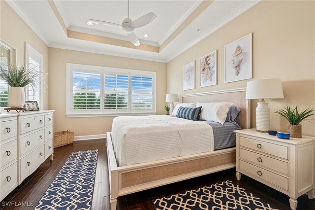 bedroom featuring dark hardwood / wood-style flooring, ornamental molding, ceiling fan, and a raised ceiling