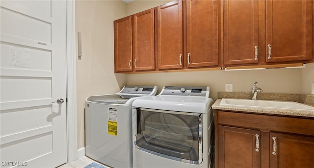 laundry area with washing machine and dryer, cabinets, sink, and light tile patterned floors