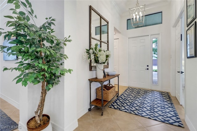 tiled foyer entrance featuring a notable chandelier and ornamental molding