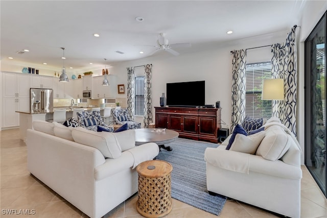 living room with ceiling fan with notable chandelier, crown molding, and light tile patterned flooring