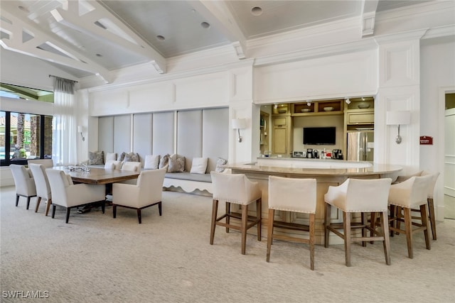 dining room featuring beamed ceiling, light colored carpet, indoor bar, and ornamental molding