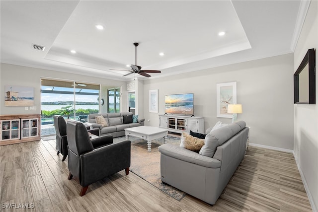 living room with a tray ceiling, ceiling fan, light hardwood / wood-style flooring, and crown molding