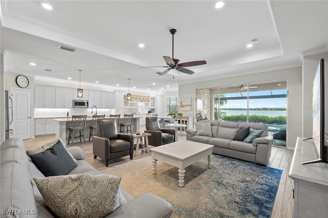 living room with ceiling fan, crown molding, and light hardwood / wood-style floors