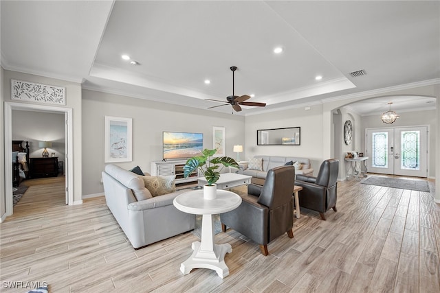 living room with french doors, ornamental molding, a tray ceiling, ceiling fan, and light hardwood / wood-style floors