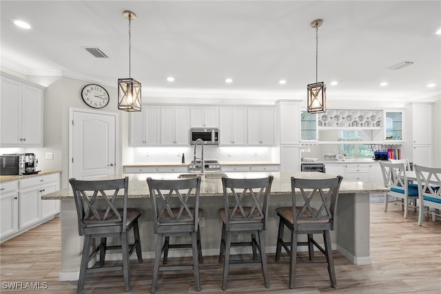 kitchen with a center island with sink, light wood-type flooring, and a breakfast bar