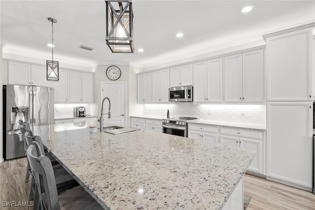 kitchen with pendant lighting, stainless steel appliances, white cabinetry, and a large island