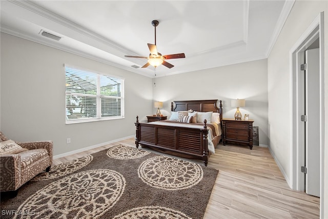 bedroom featuring a raised ceiling, light hardwood / wood-style flooring, ceiling fan, and crown molding