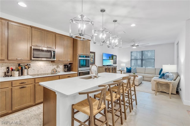 kitchen featuring tasteful backsplash, a center island with sink, stainless steel appliances, pendant lighting, and a kitchen breakfast bar