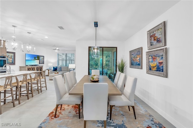 dining area with ceiling fan with notable chandelier and sink