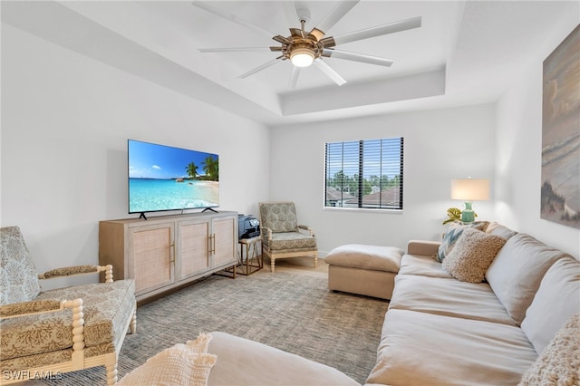 living room with ceiling fan and a raised ceiling