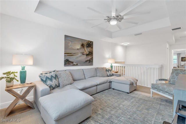 living room featuring ceiling fan and a tray ceiling