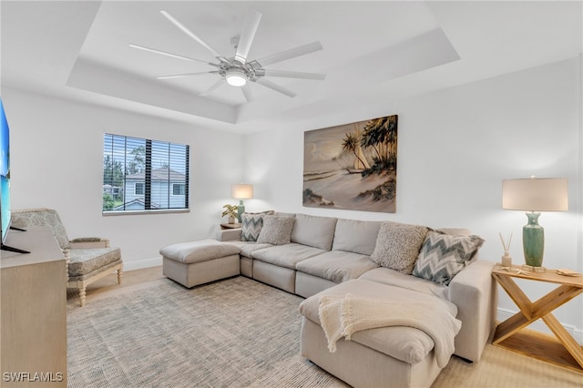 living room featuring ceiling fan and a raised ceiling