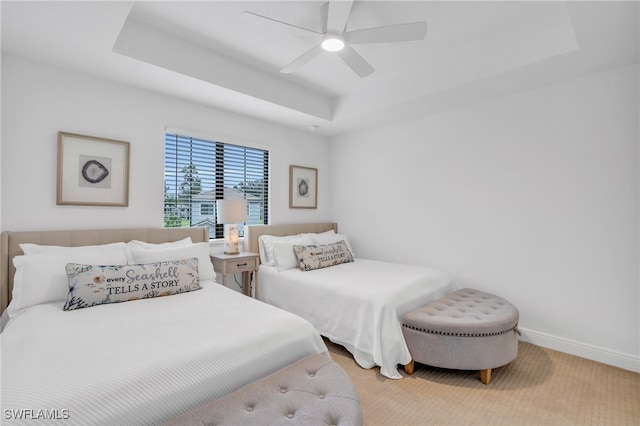 bedroom with ceiling fan, carpet flooring, and a raised ceiling