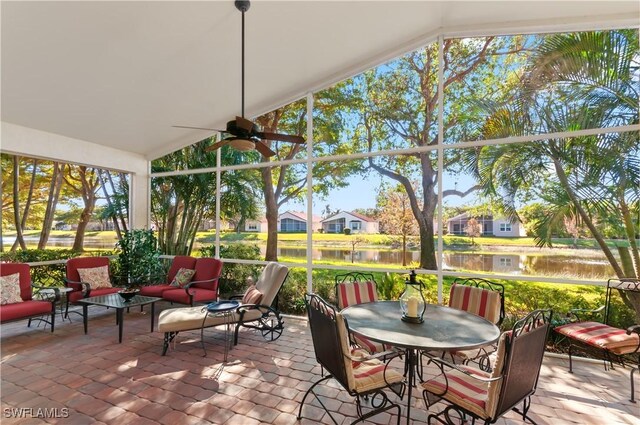 sunroom with ceiling fan, a water view, and vaulted ceiling