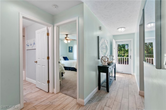 hall with light hardwood / wood-style flooring and a textured ceiling