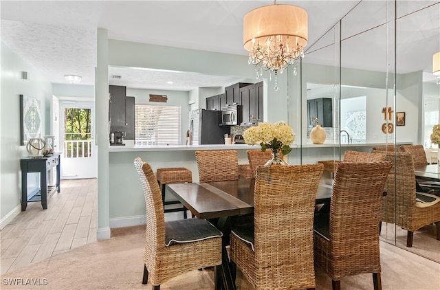 carpeted dining area with a textured ceiling and an inviting chandelier