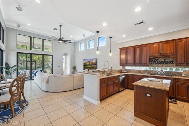 kitchen with ceiling fan, light stone countertops, decorative light fixtures, a center island with sink, and appliances with stainless steel finishes