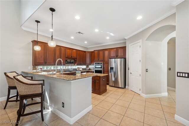 kitchen with pendant lighting, light stone countertops, appliances with stainless steel finishes, light tile patterned flooring, and kitchen peninsula