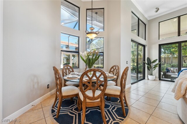 tiled dining area featuring a towering ceiling and ornamental molding