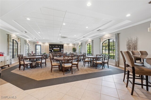 dining room featuring light tile patterned floors, a raised ceiling, and ornamental molding