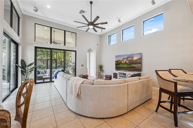 tiled living room with ceiling fan, a towering ceiling, and ornamental molding